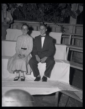 A young boy and girl sit together while posing for a photo.