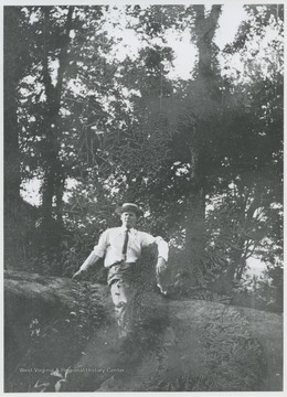 Man identified as U. G. Ryalls lounging on a log in Wyoming County, W. Va.