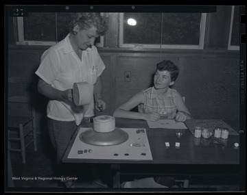 A young girl and woman making earrings. Subjects unidentified. 
