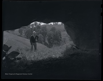 An unidentified man looks into a cave that contains Native American cave writings. 