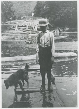 Boy identified as Algie Cook standing with dog in a flooded boat on Guyandotte River in Wyoming County.