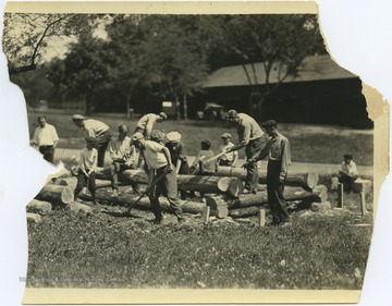 A group of men and boys assemble a log cabin. Subjects unidentified. 