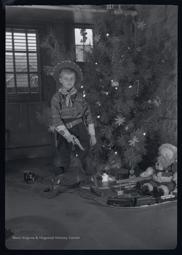 Miller Murrell dressed as a sheriff next to a Christmas tree.  He is in the basement of the Murrell family home at 309 Ballengee Street, Hinton, W. Va.