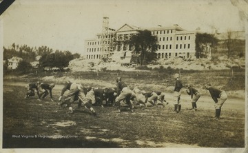 Football players practice while construction of Woman's Hall, now Stalnaker Hall, goes on in the background. Subjects unidentified. 