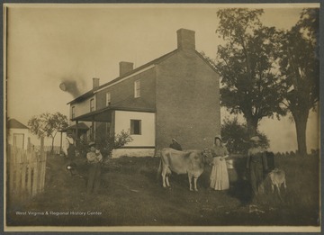 Two women, two men, one boy, and several animals in front of a farmhouse.  Note on reverse suggests that this could be Harpers Ferry, W. Va.  Photo identified as Mable Strickland's home as a child, but does not indicate if she is in the image.