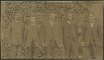 Five men, identified as the president and normal teachers of the West Virginia Colored Institute, pose in front of a building.