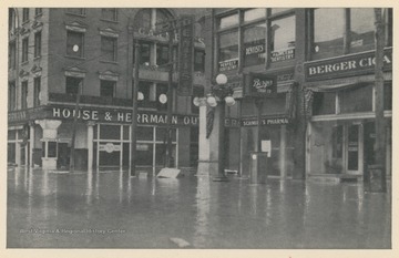 Photo postcard of 14th and Market Streets during a 1913 flood in Wheeling, W. Va.  The House & Hermann department store building is visible, as are other businesses and signs. Postcard is part of a souvenir book of 1913 flood images.