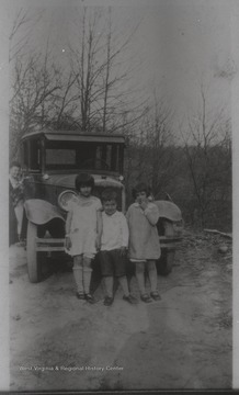 Edith Leontine Stephens (left), Gerald Otis Stephens (center), and neighbor girl Peggy Davis (right) stand beside an old-fashioned automobile. Edith and Gerald are the children of Eschol Lee and Essie Pearl Layfield Stephens. Eschol is the son of Leaman Clark Stephens, and the grandson of Stacy Stephens.