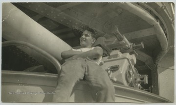 An unidentified crew member leans against the 5" gun and port. 