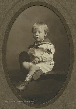Fred was the son of Fred and Pearl Gibson and the grandson of Maggie L. Gibson. He is wearing a sailor outfit and holds a small stuffed animal.