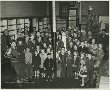 Miners of the Zephyr mine and their wives and children are gathered in front of a Christmas tree. Circled in the photograph is Rush Meadows, a mining engineer and operator from Charleston, W. Va.