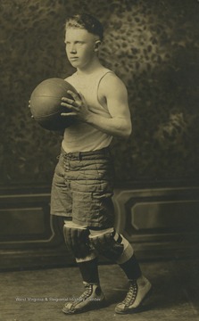 Photo postcard of John Edward Hallam. Hallam poses for a basketball photo at White School in Fairmont W. Va. He later married Stella Gattian. 