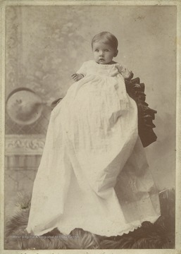 Baby Stella is dressed in a long white gown. 
