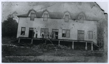 A group of men are pictured on the porch of the building. Subjects unidentified. 