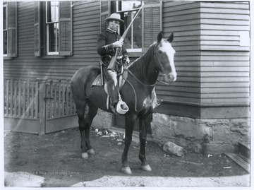 A man in a police uniform sits on top of a horse while holding a gun. 