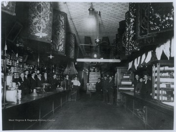 View of the building's interior, where men and women shop workers pose behind the store counters. The building, believed to be built in 1884, was still standing at the time the caption was written.