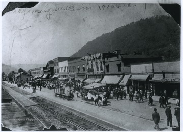 View of the town's main street which is situated next to railroad tracks.  The train station is visible at the far left, while businesses line the street.