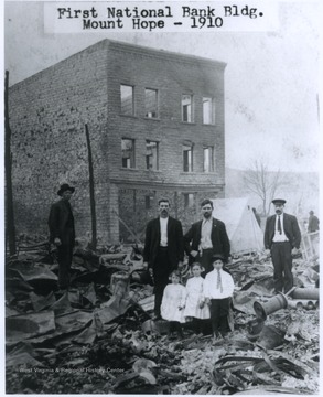 Men and children stand in front of the remains of the First National Bank building. Large swaths of town were destroyed during the fire.