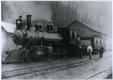 The engine used oil headlights. Five men are pictured on and beside the locomotive. 