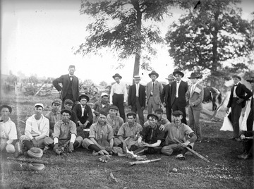 The players pose together for a team portrait. Two men in the background are sporting American flags on their jackets and hats, perhaps indicating it is Fourth of July. 