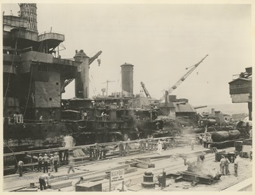 "The W. Va. is shown as she was photographed at a dry dock in Pearl Harbor. The battleship was severely damaged in the Japanese raid Dec. 7, 1941. Damages to her sides are visible."