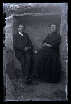 A man and his wife sit in what it possibly the cellar of their newly built home. 