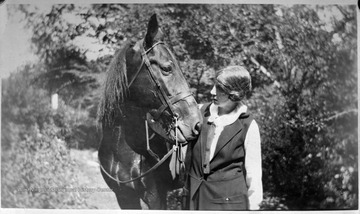 Duesenberry speaks to the horse as she walks it along a trail. 