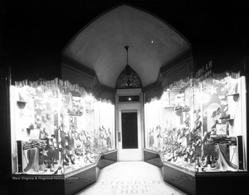 A variety of women's shoes are displayed in the windows by the entrance to the shop. 