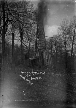 An oil derrick is pictured in the woods. 