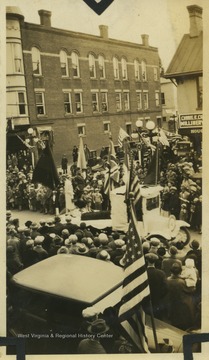 A parade float passes buildings and spectators on High Street.