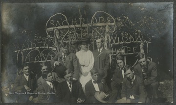 Pictured standing are E. B. Schiltz (left), Mrs. H. A. Lane (center), and H. A. Lane.Pictured sitting, from left to right, are D. R. McKibbin; an unidentified Q & C. (Queen and Crescent) Route agent; W. H. Koppleman; H. H. Hartlove; W. C. "Riney" Rinearson, Jr.; F. S. "Danny" Dannenberg; Willie Knight, Heinie Miller; and Mr. Hennessy.The group poses in front of a structure that reads, "Maiden's love, Bachelors rest, Widows hope."This photograph is found in a scrapbook documenting the survey for the Baltimore and Ohio Railroad in West Virginia and surrounding states. 