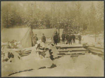 Surveyors stand beside the tents and observe the "Beautiful Snow !*?!!".This photograph is found in a scrapbook documenting the survey for the Baltimore and Ohio Railroad in West Virginia and surrounding states. 