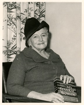 Portrait of Pearl S. Buck holding a copy of her book, "My Several Worlds," originally published in 1954.