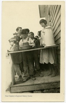Group of children standing on a porch.