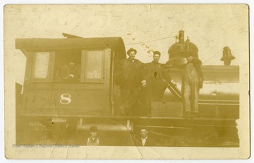 A group of men pose in and on an engine of the M and K Railroad. 