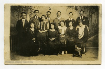 Front left to right: Mrs. Marchand, Miss Taylor, Miss Lowe, Mrs. Mackenzie, Mrs. Hoffman. Back row left to right: Clarence Marchand; Wm Morgan; Wm Wilson; Fred Troup; Wm Mackenzie and Geo Hoffman.  William Wilson is identified with an X.