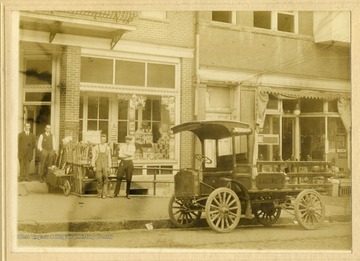 Four men stand near a delivery truck outside a hardware store on Walnut Street.