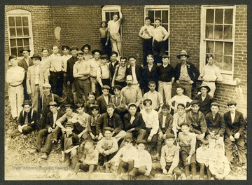 A large group of young male glass workers pose outside of the Seneca Glass Factory in Morgantown. 