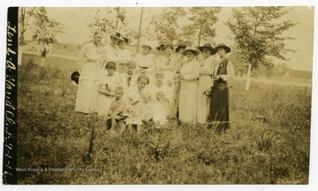 Club members, including women and children, pose for photo in a field.