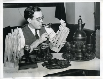 Text on the back reads, "Washington, D. C.: Senator Rush D. Holt, of West Virginia, in the capital on the eve of opening of congress, examines some of the wood carvings he collects as a hobby. The 'glasses' and the decanter are also carved of wood."