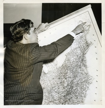 Text on back reads, "Senator Rush D. Holt, of W. Va., youngest Senator who fought for moths to gain his seat on the floor, today celebrated his 34th birthday. He is shown looking over a map and pointing out Alcide, New Brunswick, Canada where residents said they heard an explosion at about the time Thomas H. Smith, ocean flier, was due to fly overhead. It is now feared that Smith's plane may have exploded and crashed in a thickly wooded area of that section. Smith had been personal pilot for Senator Holt and had named his plane for him." 