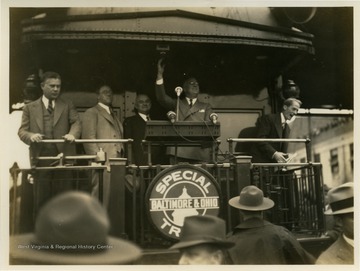 Franklin D. Roosevelt pictured standing at podium on Baltimore and Ohio train car.