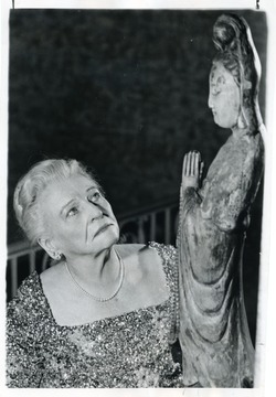 Caption on back reads, "Pearl Buck, author of many books and winner of Nobel Prize for Literature, studies a twisted-root carving of an old Chinese man."