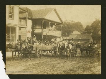 "Picnic group leaving Rutherford Hotel for Whittaker Falls about 1912.First wagon, left to right: Isaac Curry, Doy Rutherford, Hawes Thurmond with large hat, Goodrich White, Garrett Thurmond, Ben Hamrick, Beatrice Cogar, Belle Wethered, R. Moore Dodrill, Eula Thurmond, Eva Lowe.Second wagon: Zetta Stanard, Mrs. S. P. Allen, Attorney H. C. Thurmond, 'Doc' White.Buggy: Faye Thurmond, Roy Rutherford, Kate White. Mrs. Arch Rutherford is on balcony. Unknown observer is in background. Photo was preserved by Mrs. Faye Thurmond Meeker of Charleston, W. Va."