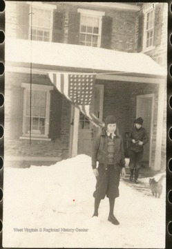 Boy standing in front of house on winter day. 