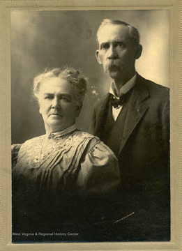 Back of photo describes the couple's appearance. Mr. Kelley is described as: "hair - brown grey. eyes - brown. mustache - grey. tie - black." Mrs. Kelley is described as "hair - brown grey. eyes - blue. [illegible] - fair. black frame. black & white plaid [illegible, possibly dress]. collar - Irish point lace."