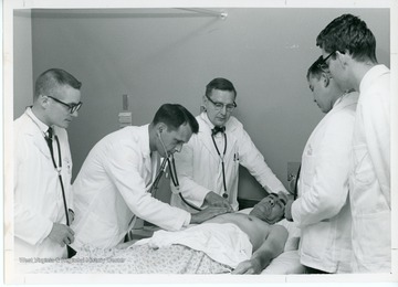 Medical students perform an exam on a patient.