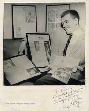Rod Hundley sitting with his many sports clippings and frames.