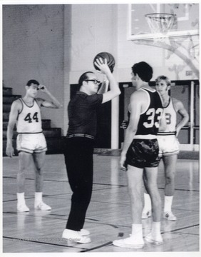 Rene Henry jokingly shows Jerry West (44 jersey), Rod Hundley (33 jersey), and Pat Riley (3 jersey) how to shoot a three pointer for a film shoot.