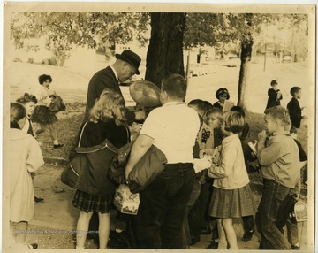 Charles Whiston showing off his balloons to a group of children.